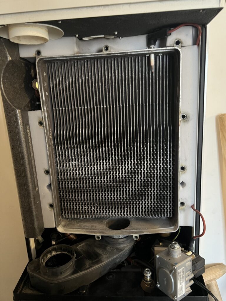 Geopende cv-ketel met de warmtewisselaar in zicht
